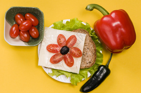 钟素食主义者叶子在黄色背景的白盘子上加蔬菜的三文治明图片