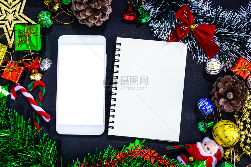 丝带圣诞节新年概念黑纸背景上空智能手机笔记本和铅的圣诞喜庆装饰品最佳图像新年概念移动的图片