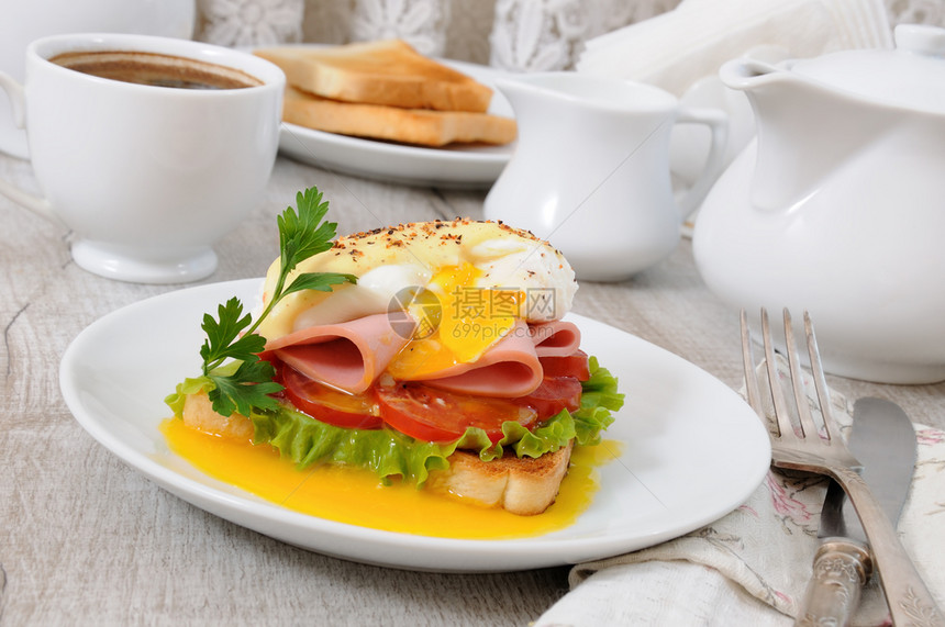 烤火腿和西红柿本尼迪特鸡蛋加荷兰酱早餐饮食的肉汁面包图片