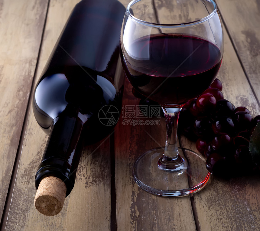饮料瓶子美食酒红杯和葡萄瓶在旧木制桌上装满玻璃和葡萄的酒瓶图片