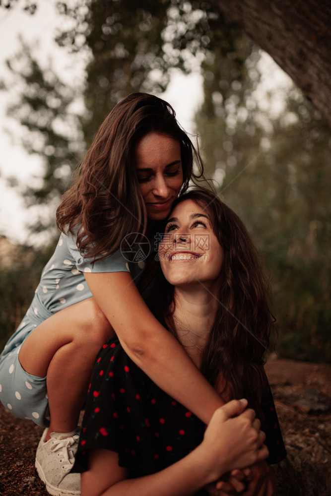 快乐的爱外部两名女青年在田间拥抱身着裙子的女者图片