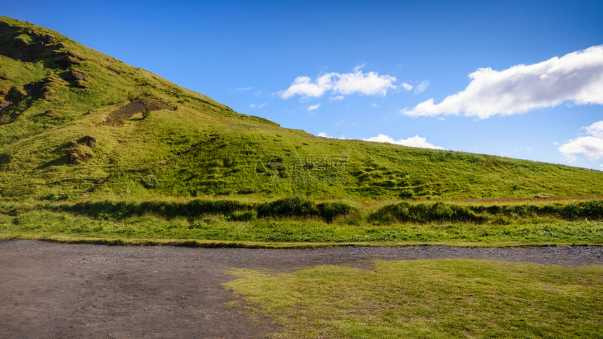 在冰岛Skogafos的蓝色天空中美丽的山脉有选择地聚焦在冰岛Skogafos草浪漫的绿色图片