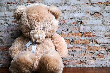 一只毛熊用旧砖墙坐在木地板上单身的可爱玩具高清图片