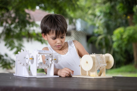 有创造力的教育一个男孩子注意学习模拟机制在家里桌上的木制机器人模型板机设计师背景图片
