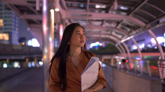 屏幕美丽的年轻女士在夜市街道上行走身处城市深夜商业沟通图片
