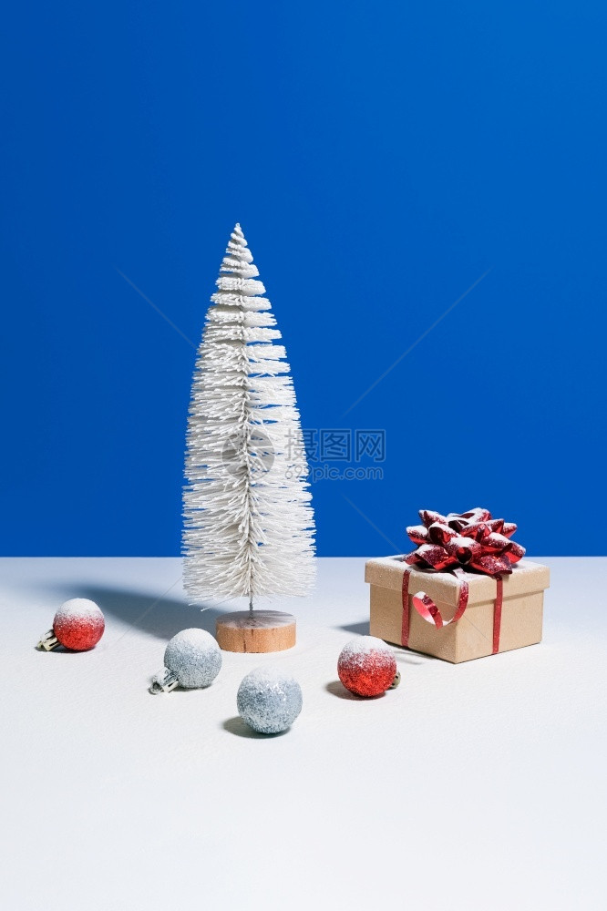 新的流行音乐美丽圣诞节或新年横幅玩具圣诞树带红色蝴蝶结的礼品盒和蓝色背景的圣诞小玩意美丽的圣诞节或新年横幅玩具圣诞树带红色蝴蝶结图片