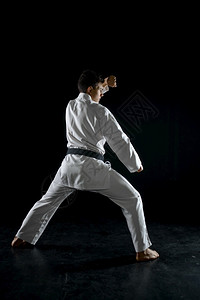 战斗机冲床男空手道拳在战斗姿势中黑暗背景男子在空手道锻炼武术打斗比赛上男空手道拳在战斗姿势中白色的背景图片