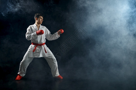 专业的白和服红手套的男空道斗士战姿势运动方面的黑暗背景拳手武术比赛前训练白和服的男空手道斗士和红套竞赛运动员背景图片