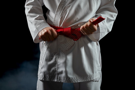 冲床白和服的男空手道斗士有红带战姿势黑暗背景的空手道运动武术在比赛前训练白和服的拳手有红腰掌握强的背景图片