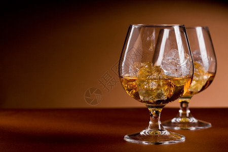 静物照片美味的白兰地威士忌杯子棕色背景的冰块水复制背景图片