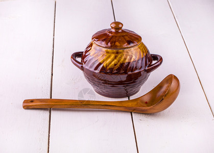克鲁斯白色木质背景上的旧瓦罐烹饪和木勺优质的图片