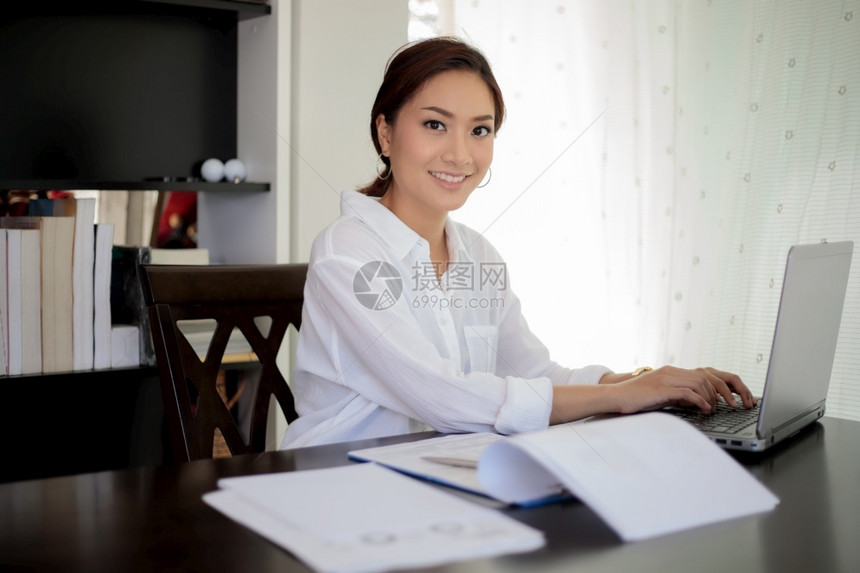 成人年轻的坐着使用笔记本的亚洲商业妇女为工作而笑高兴图片