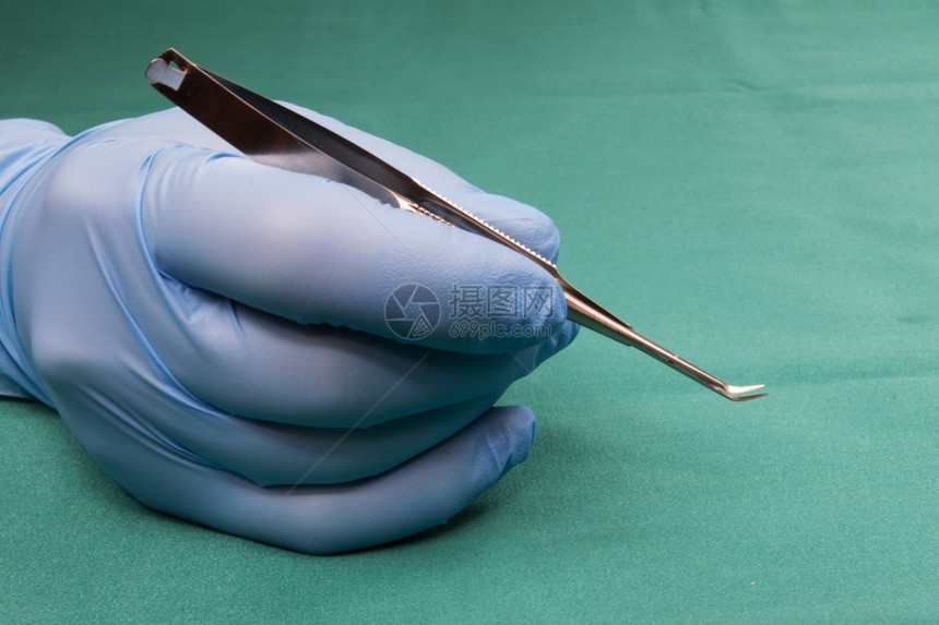 科学保持药物外医生有微型外科手术工具蓝色套的刀软曲线蓝手套中的野生医手拿着剪刀软曲线背景是蓝桌布操作图片
