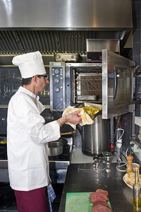 2012年7月选择第4周油一位厨师将盘土豆放入专业烤箱单身的厨房背景