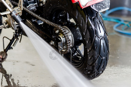 一个用高压水洗摩托车的男士擦拭骑毛巾图片