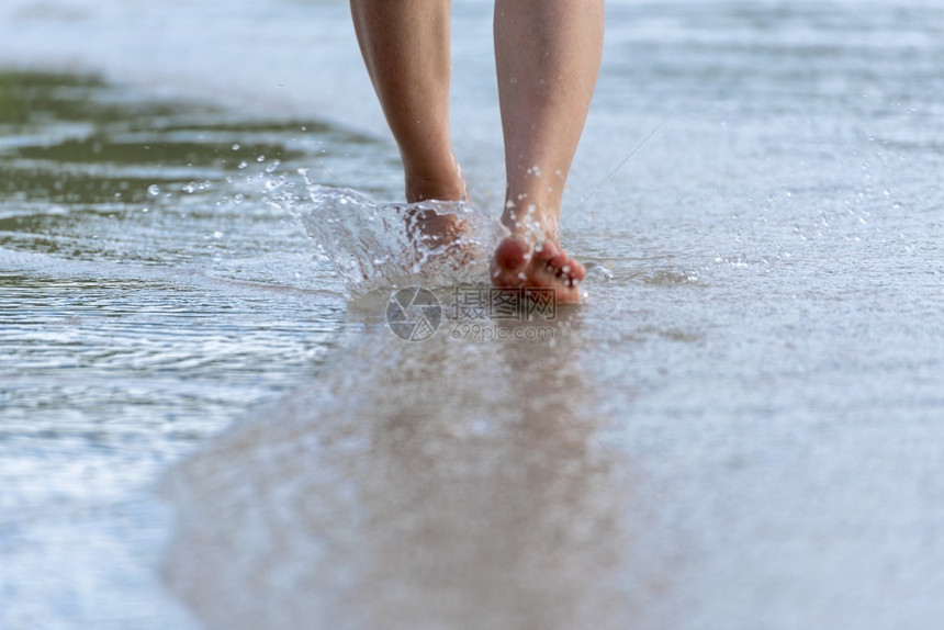 海岸离开妇女赤脚在夏季沙滩上徒步行紧闭年轻女子的腿她们在海滩旅行概念组织上沿着海水和沙浪行走年轻的图片