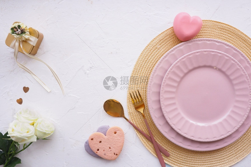 花朵桌子上设置餐巾纸两张粉红板饼干心金礼品盒三个白玫瑰花芽勺子和叉放在一张白色桌上复制平板空间布局二月天图片