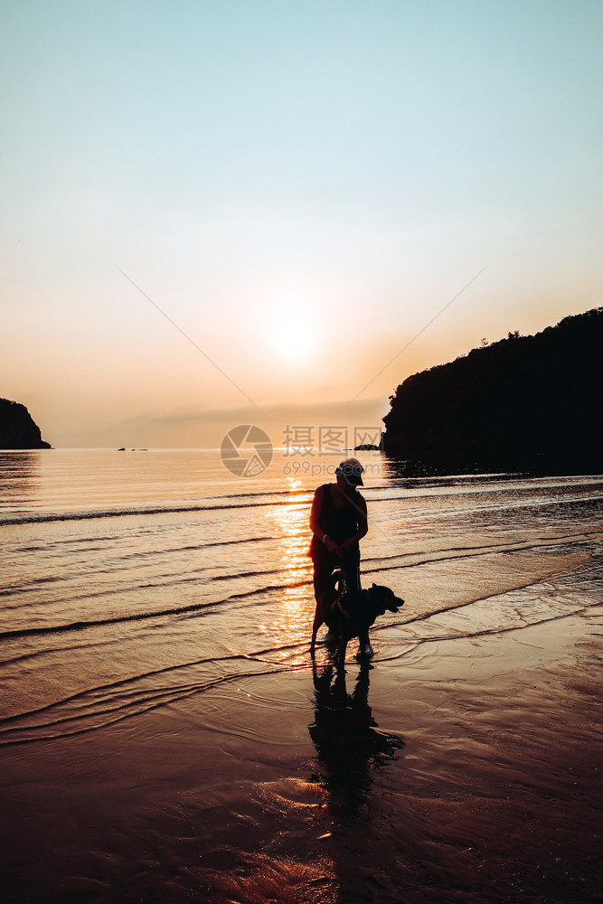 海滩摄影日出时沙上的高级女子和狗犬类图片
