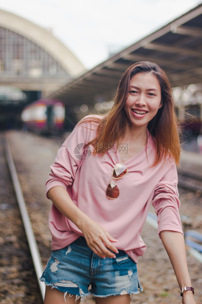 穿粉红大衣的女孩站在铁轨上的路走车站一种图片