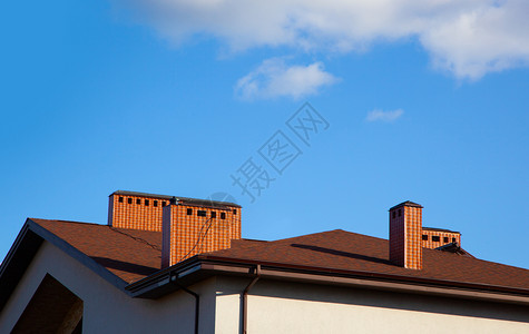 窗户房子有砖烟囱阳光明亮面对深蓝色的天空在房顶上的香尼丝在蓝天闪烁家图片
