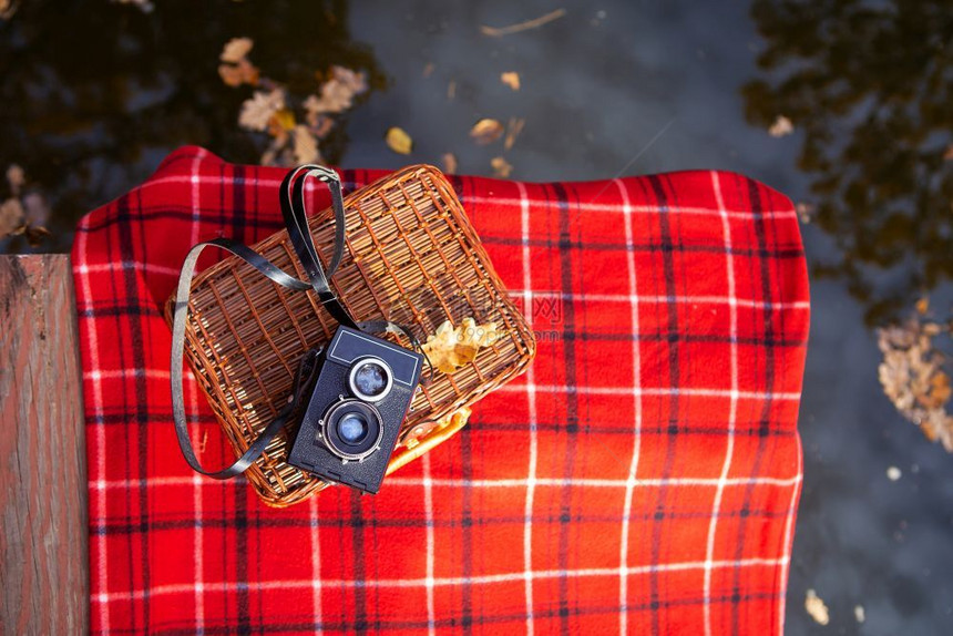 乡村笼熊旧相机放在红色格子毯上的手提箱湖边木桥旧相机放在红色格子毯上的手提箱图片