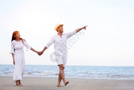 海边手牵手散步的情侣图片
