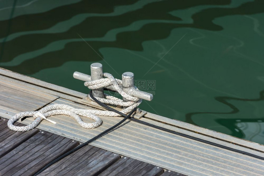 航海的帆船绑在木制码头的一扇锁链上用绳子系住索水图片