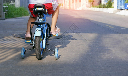 市郊女孩近视和低段儿童骑自行车上午在街用培训轮子驾驶街头车户外图片