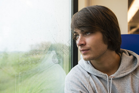 兜帽观察看青年男子在火车中旅行展望窗外图片