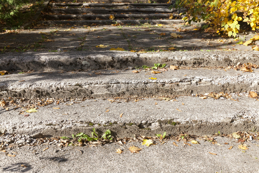 脚步一种秋季有落叶的古老水泥楼梯上面盖着秋季落叶的旧水泥楼梯这些本身又旧了混凝土楼梯因此造成许多损坏覆盖图片