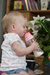 健康童年关心用瓶子喝奶的孩可爱的婴儿肖像用瓶子喝牛奶的孩可爱的婴儿图片