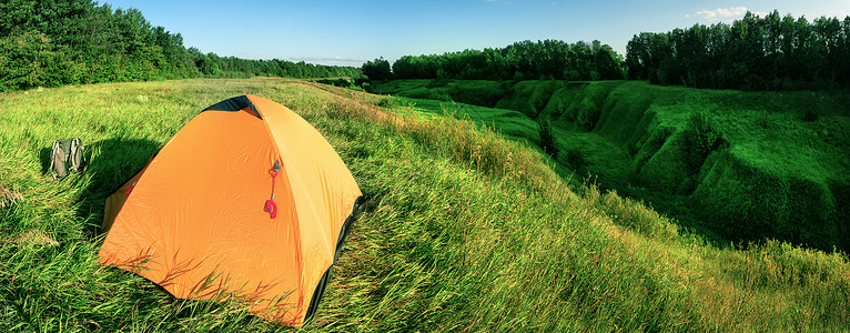 峡谷上的绿色山坡橙色帐篷旅图片