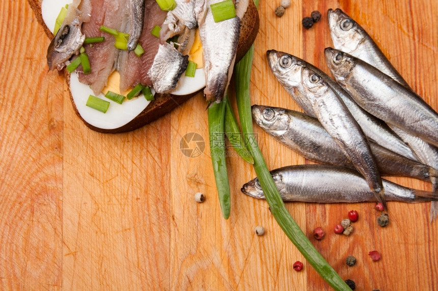 渔业三明治以含蛋的咸鱼和木头上春天洋葱为原料食物图片