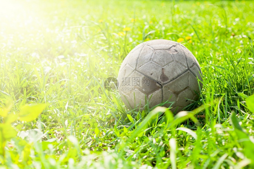 阳光旧足球在绿草田中被遗忘的旧足球橄榄的概念绿色沥青图片