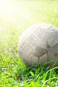 旧足球在绿草田中被遗忘的旧足球橄榄的概念杯子团队目的图片