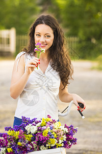 乐趣一个美丽的年轻女子骑自行车闻着野花的气味夏天旅行图片