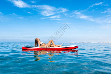 泳衣美女坐在冲浪板上享受阳光图片
