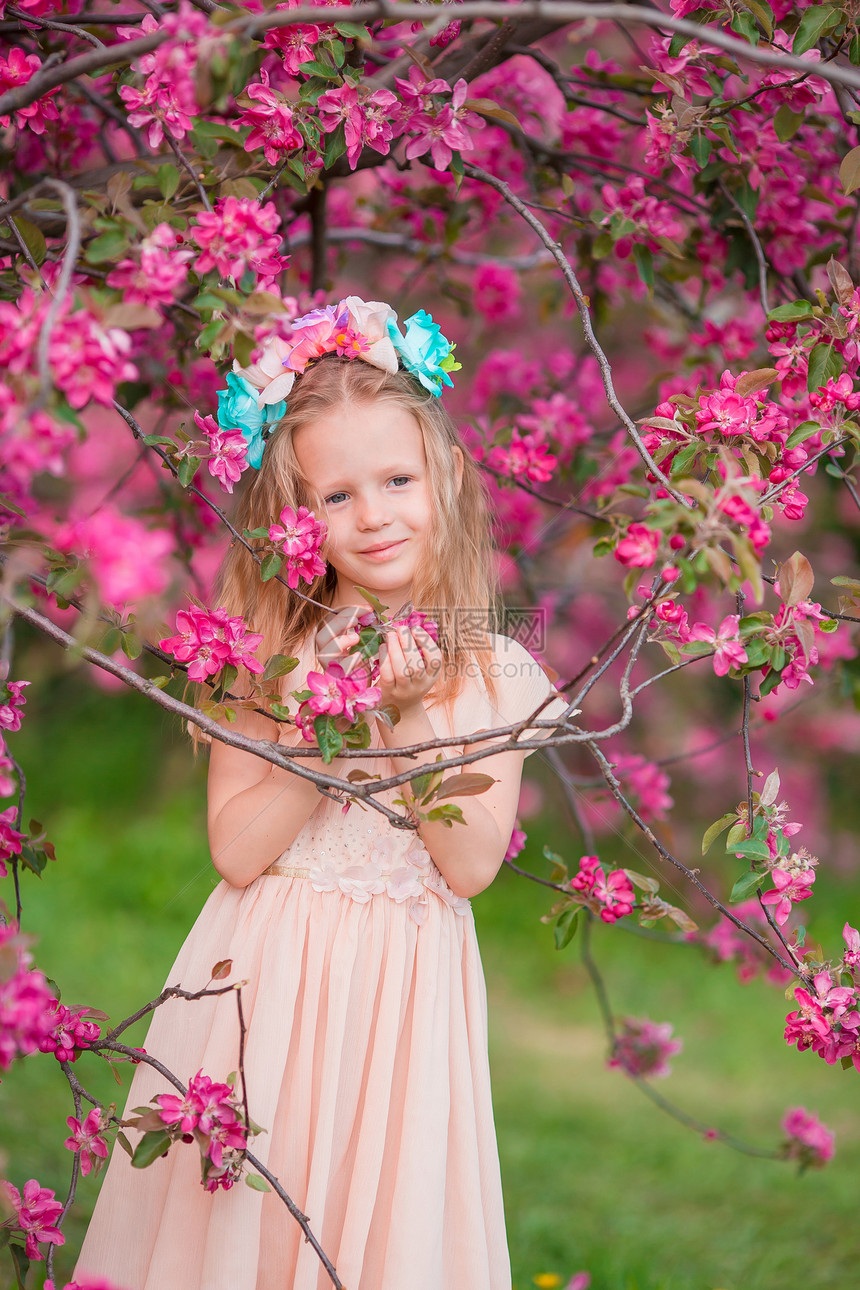 人们分支快乐的美丽小女孩在盛开的树园花美丽的春日可爱小女孩在盛开的苹果园中图片