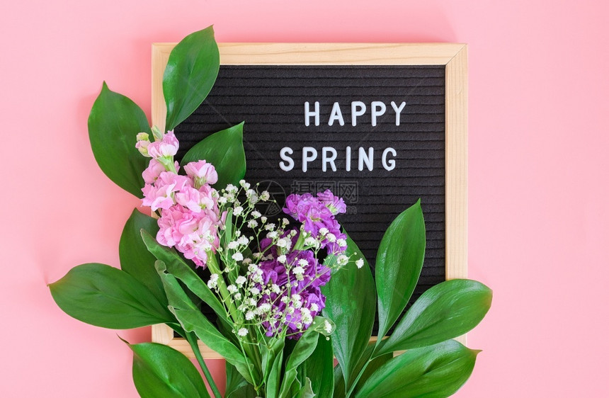 脆弱花的绽放黑色信板上的快乐春天文本和粉红色背景上的花束概念你好春天明信片的模板贺卡黑色信上的快乐春天文本和粉红色背景上的花束图片