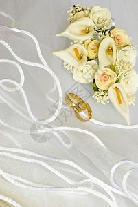 白色的婚礼珠子新娘面纱上的结婚戒指和鲜花装饰图片