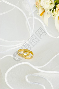 金子的新娘面纱上结婚戒指和鲜花装饰订婚图片
