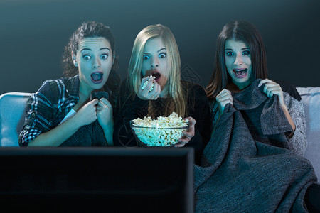 闲暇年轻女孩看恐怖电影的爆米花恐惧瘾图片
