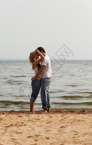 美丽的夫妻在海滩上拥抱愉快微笑常设图片