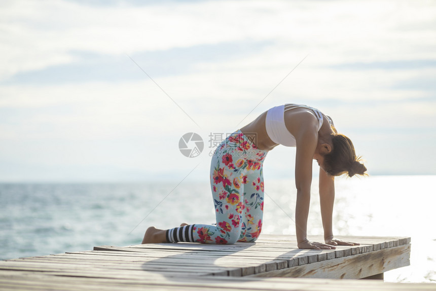户外夏天年轻女子在海码头做瑜伽姿势活动图片