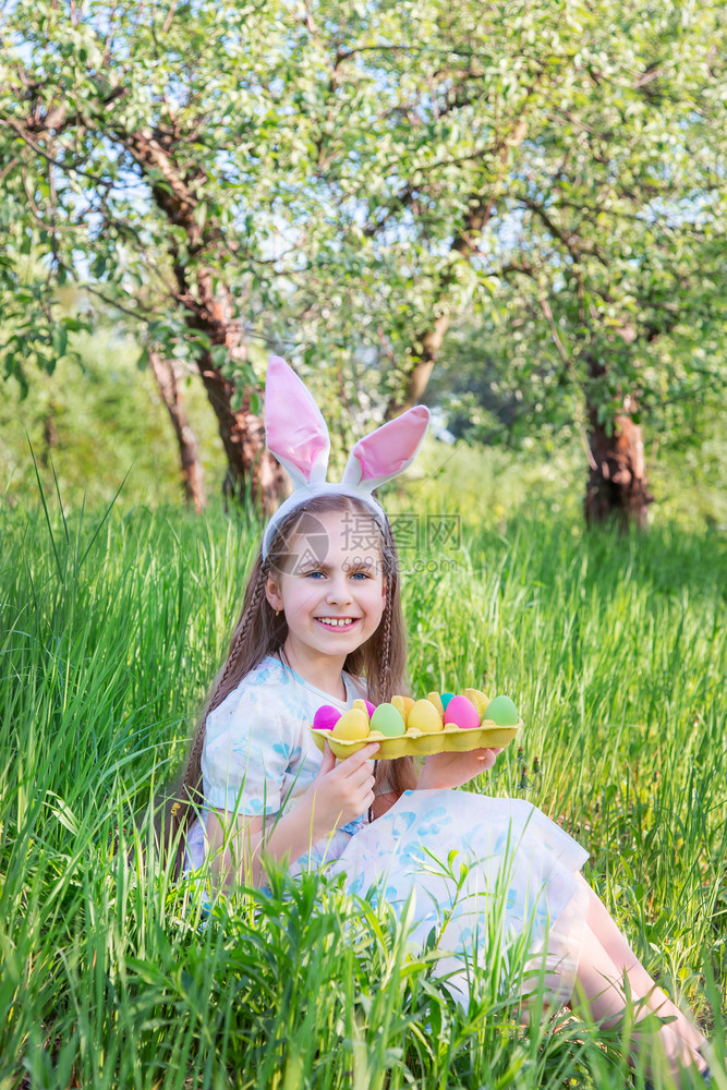 假期复活节那天长着兔耳朵的可爱女孩一个在花园里追逐复活节彩蛋这个女孩有一装满彩蛋的篮子复活节那天长着兔耳朵的可爱女孩一个在花园里图片
