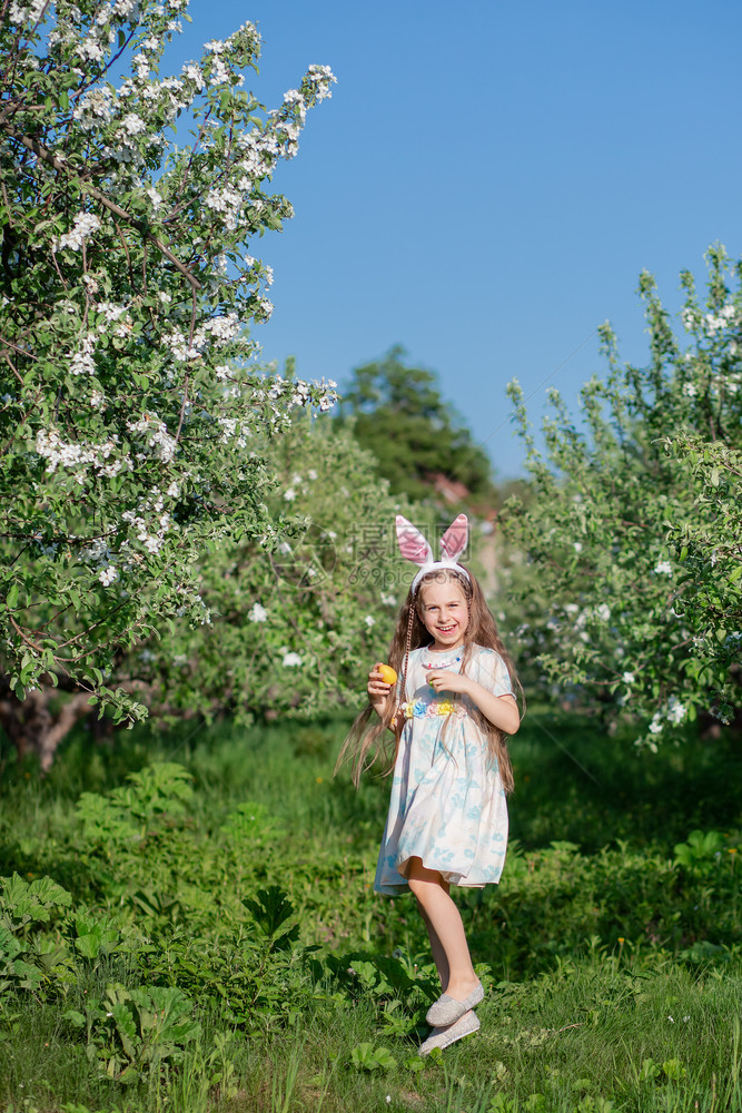 销售复活节那天长着兔耳朵的可爱女孩一个在花园里追逐复活节彩蛋这个女孩有一装满彩蛋的篮子复活节那天长着兔耳朵的可爱女孩一个在花园里图片