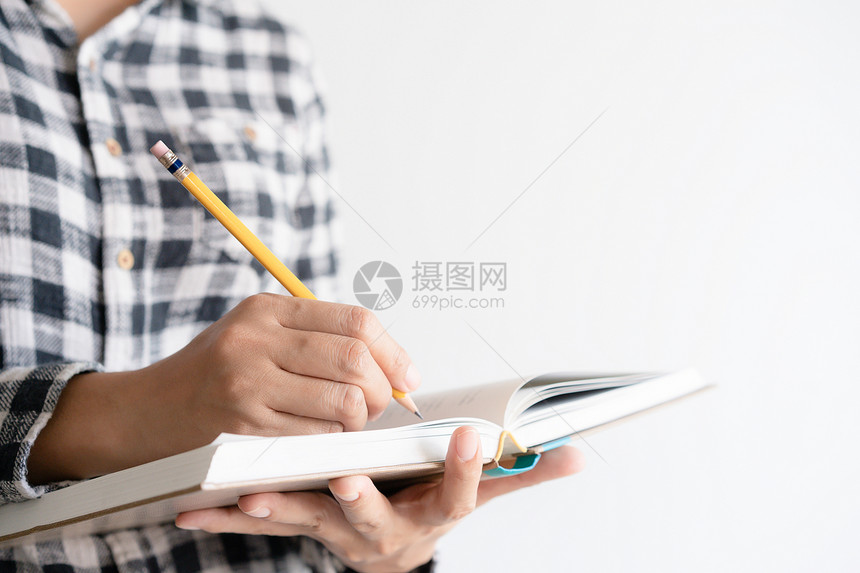 在职的成人年轻女左手拿着笔记本和右手写日女青年用手握笔记本和右写日亚洲图片