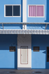 长方形屋玻璃窗户表面的阳光和阴影垂直框内蓝色建筑被遮盖在蓝墙上具体的图片
