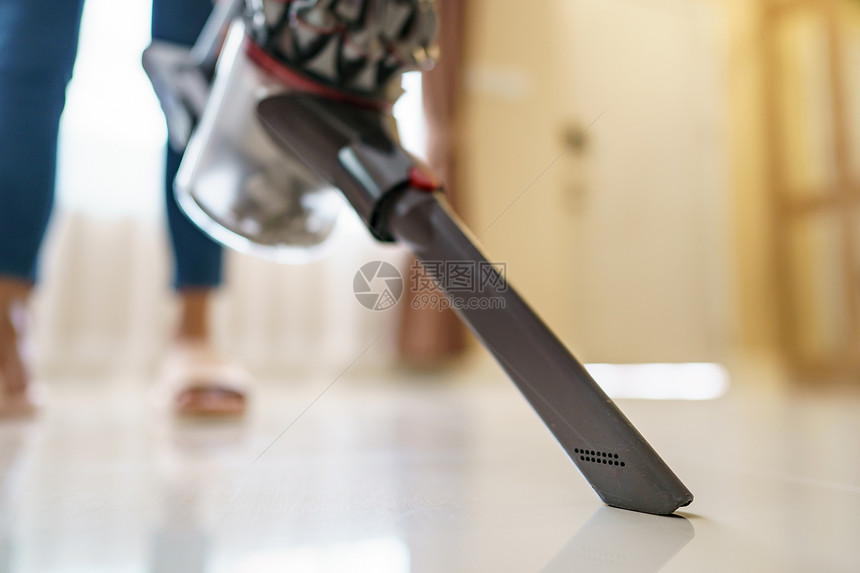 污垢女士机器妇在地板上使用真空吸尘清洗图片