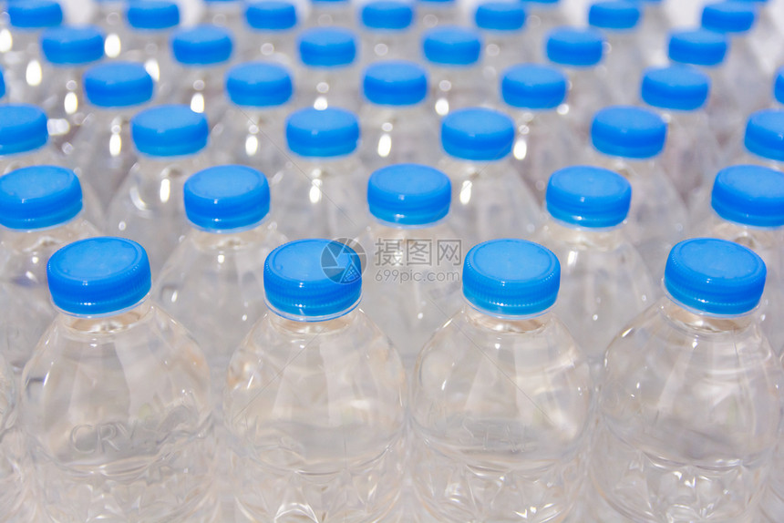 水平的透明一排瓶带蓝盖的饮用水有机的图片